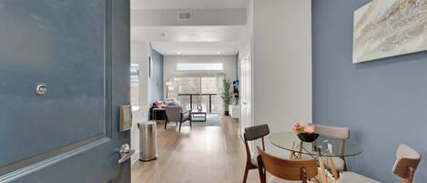 A modern interior with a dining area, a living room, and a hallway leading to a balcony.