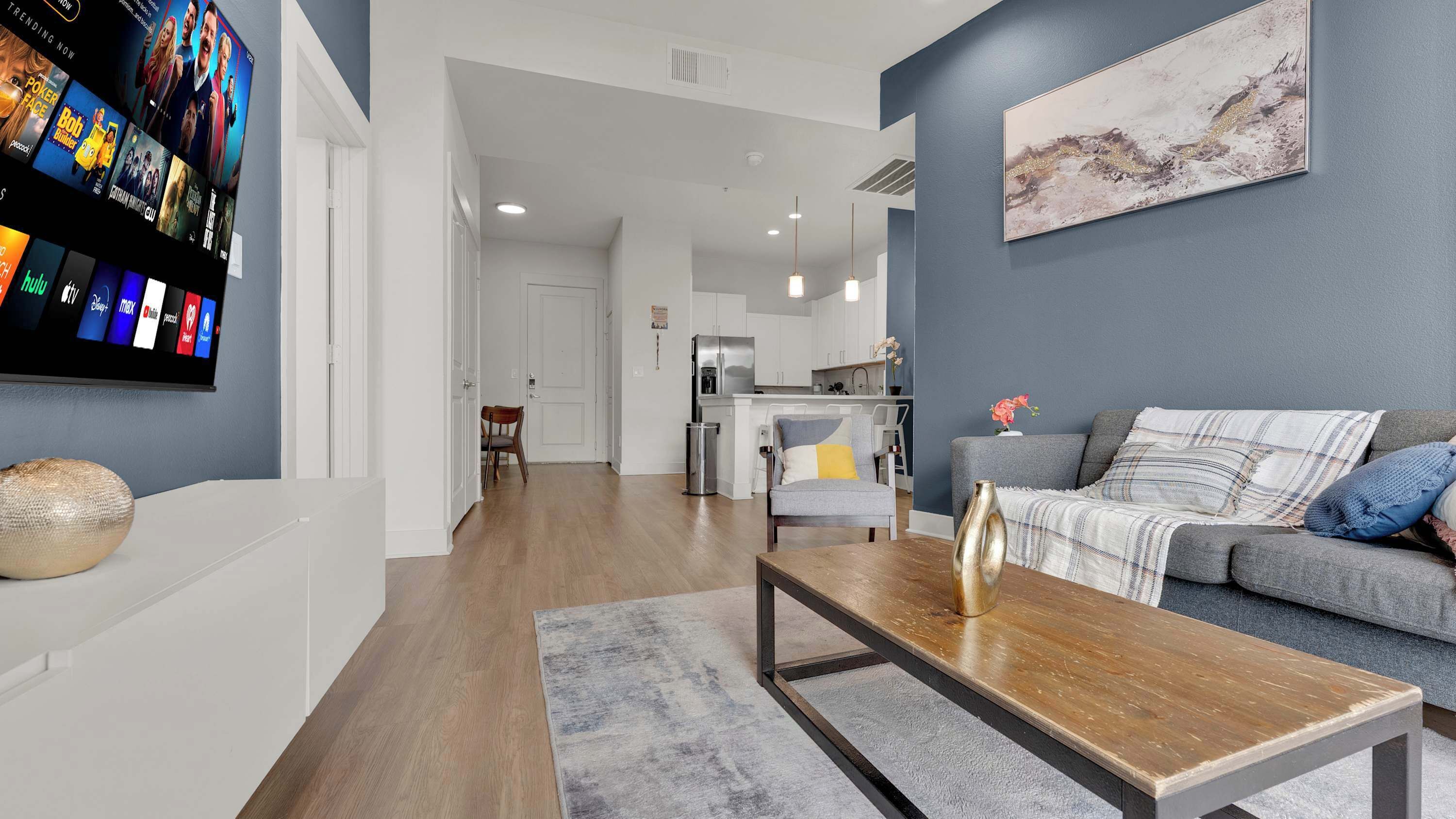 A modern living room with a flat-screen TV, a sofa, a coffee table, and a painting on the wall.