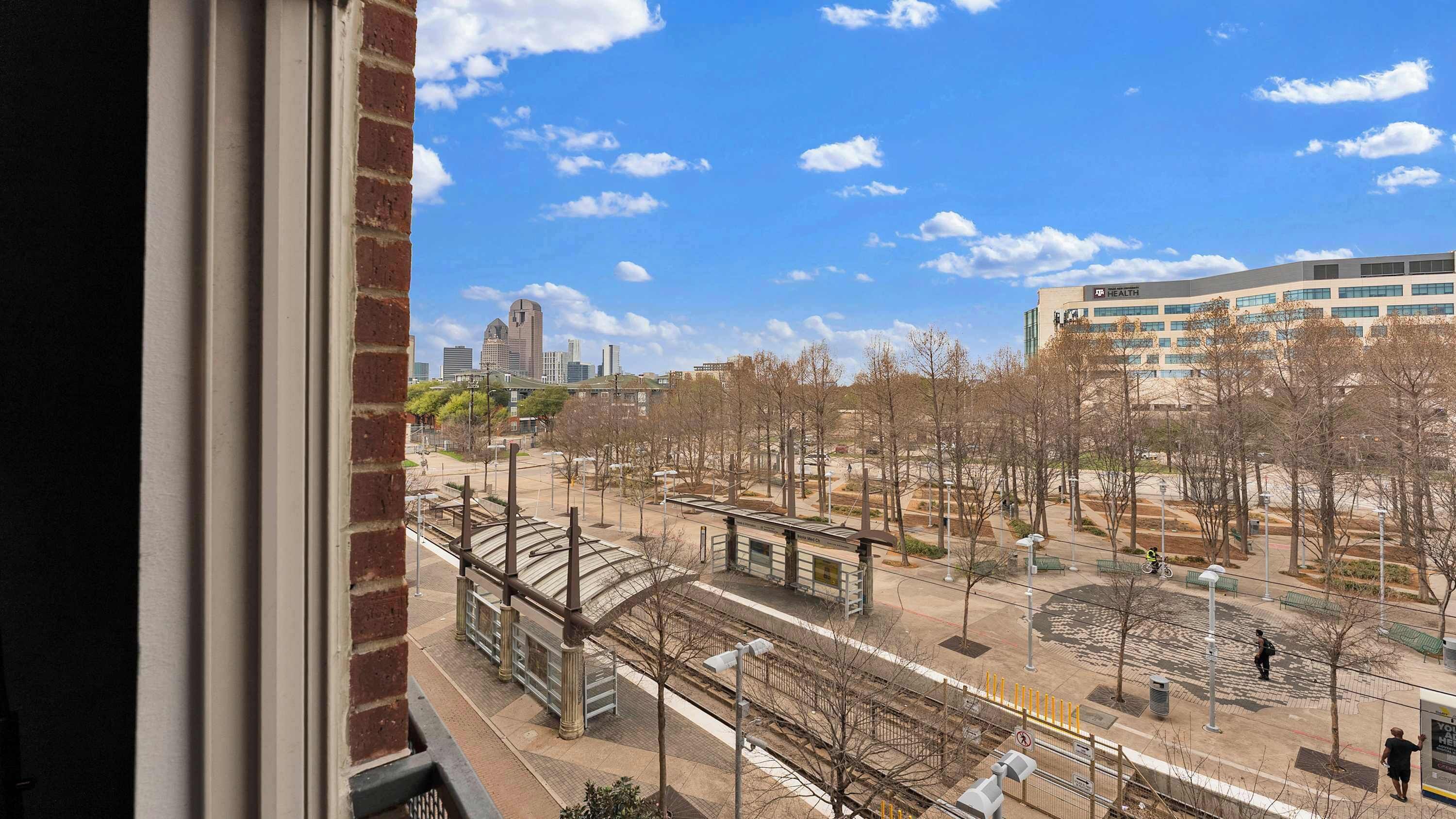 Vista de una plaza con tranvía, bancos y árboles.
