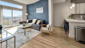 Un appartement moderne comprenant un salon, une cuisine et de grandes fenêtres donnant sur la ville.