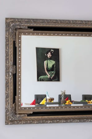 A framed portrait of a woman in a green dress on a wall.