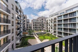 A modern multi-story residential building with balconies, a central courtyard, and a clear sky.