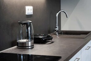 A kitchen with a coffee maker on the counter, a faucet, and a power outlet on the wall.