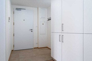 A room with a closed door, a small cabinet with a lock, and a coat rack with hooks.