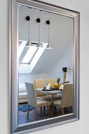 A dining area with a table set for four, a vase with flowers, and a fruit bowl.