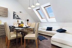A modern loft-style room with a dining area, a sofa, and skylights. - Deluxe Rabbit Suite (Prague 2)
