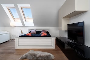 A modern bedroom with a bed, a TV, and skylights.