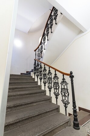 Una escalera con barandillas de metal negro ornamentadas y una barandilla de madera.
