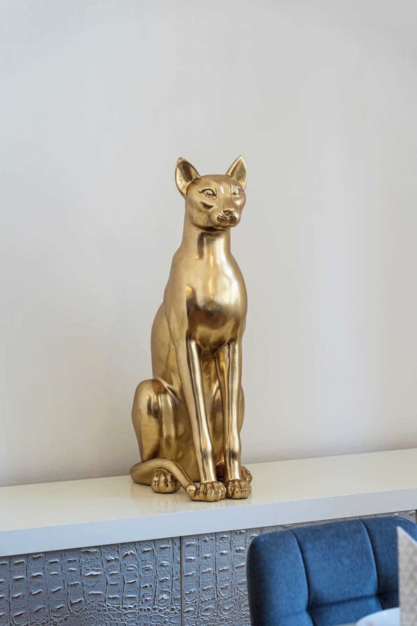 A golden cat statue on a white shelf.