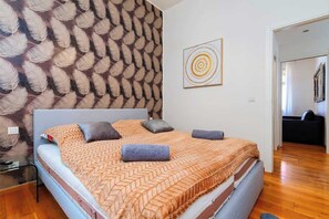 A bedroom with a patterned wall, a bed with a herringbone bedspread, and a minimalist decor. - Big Cat Residence (Prague 2)