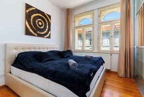 Une chambre avec un grand lit, une fenêtre avec des rideaux et une œuvre d’art accrochée au mur.