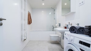 A modern bathroom with a toilet, sink, and a washing machine. - Bohemian Deluxe Suite (Prague 5)