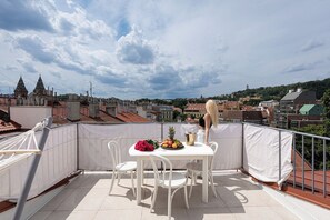 A rooftop terrace with a table set for two, overlooking a cityscape with historical buildings.