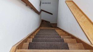 A staircase with wooden steps and handrails, leading to a landing with a coat rack. - Royal Skyline Residence (Prague 5)