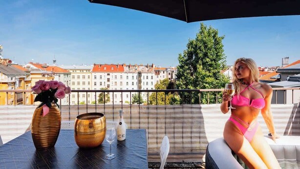 A balcony with a table, a vase with flowers, and a bottle of champagne. - Royal Elephant Residence (Prague 2)