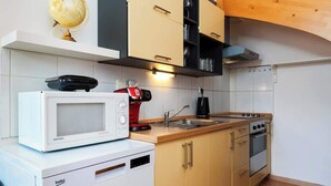 A compact kitchen with a microwave, coffee maker, and a stove. - Royal Elephant Residence (Prague 2)