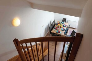 A wooden staircase leading to a dining area with a table set for a meal, chairs, and a light fixture on the wall. - Royal Elephant Residence (Prague 2)
