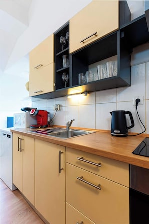 A modern kitchen with a wooden countertop, stainless steel sink, and a coffee machine.