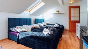 A bedroom with a sloped ceiling, a skylight, a bed with multiple pillows, a small shelf with a decorative item, and a door. - Royal Elephant Residence (Prague 2)