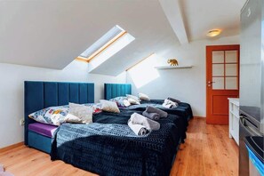 A bedroom with a sloped ceiling, a skylight, a bed with multiple pillows, a small shelf with a decorative item, and a door. - Royal Elephant Residence (Prague 2)