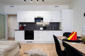 Una cucina compatta con mobili bianchi, un forno a microonde e una macchina per il caffè.
