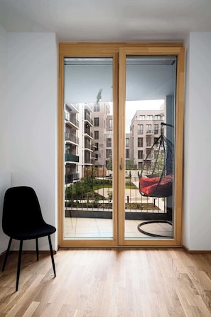 A modern room with a sliding glass door leading to an outdoor balcony with a hanging chair.