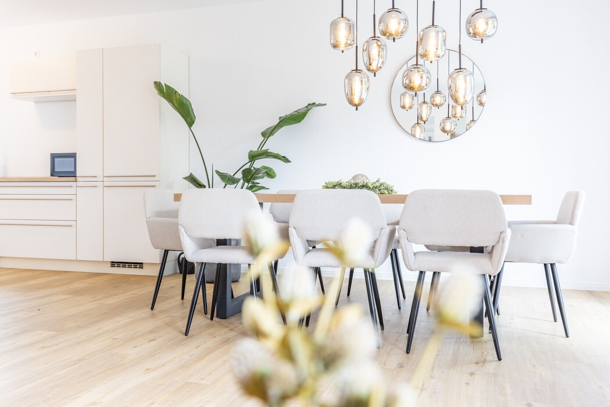 Un comedor moderno con una mesa blanca, sillas grises y una lámpara colgante.