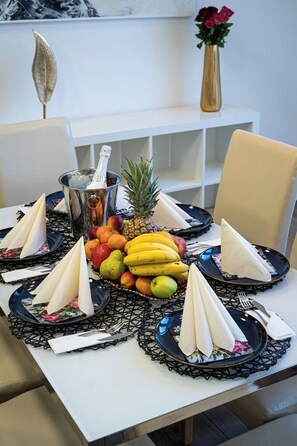 A dining table set with plates, napkins, and a fruit basket.
