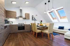 A modern kitchen with wooden cabinets, a dining area with chairs, and a sofa.