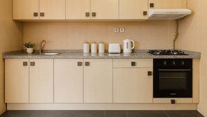 Une cuisine moderne avec des meubles de couleur beige, un plan de travail en granit, une cuisinière, un four et une machine à café.