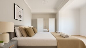 Une chambre d’hôtel moderne, équipée d’un lit, d’une table de chevet, d’une lampe et d’un tableau encadré au mur.