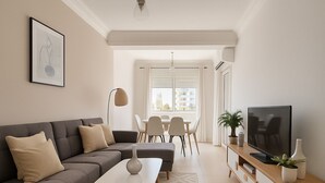 Un salon moderne avec un canapé gris, une table basse blanche, un téléviseur posé sur un meuble en bois et un coin repas comprenant des chaises et une table.