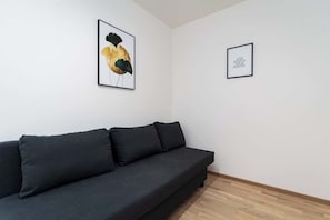 Un salon moderne avec un canapé gris foncé, deux œuvres d’art encadrées accrochées au mur et un plancher en bois.