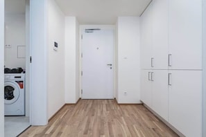 A hallway with a washing machine, white cabinets, and a door with a handle.