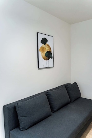 Uma sala de estar moderna com um sofá cinza escuro e uma obra de arte abstrata emoldurada na parede.