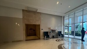 Eine großzügige Lobby mit Fliesenboden, einer Rezeption und einem großen Fenster mit Blick nach draußen.