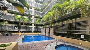 Ein Pool auf dem Dach mit einer Holzterrasse, umgeben von üppiger Vegetation und moderner Architektur.
