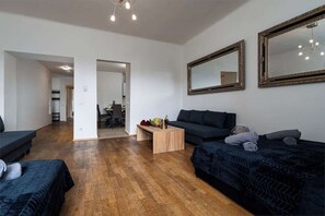 A modern living room with a dark sofa, a wooden coffee table, and two large mirrors on the wall.