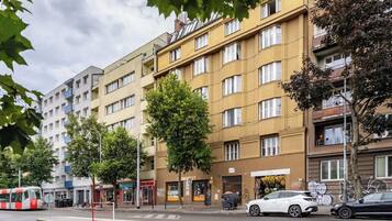 A multi-story residential building with balconies, a tram line, and parked cars.