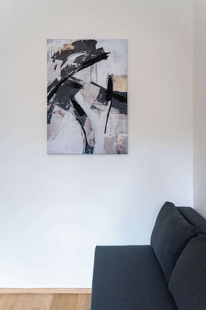A modern living room with a large abstract painting on the wall and a dark-colored sofa.