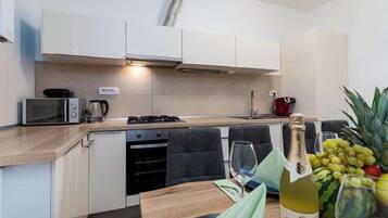 A modern kitchen with white cabinets, a microwave, a coffee maker, and a wine bottle on the counter.
