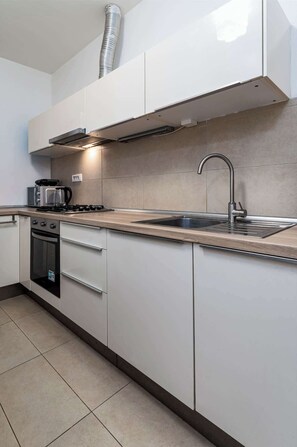 A modern kitchen with white cabinetry, a stainless steel sink, and a built-in oven.