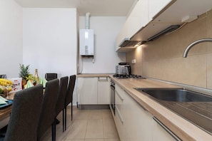 Una cocina moderna con estufa a gas, pileta de acero inoxidable y horno integrado.