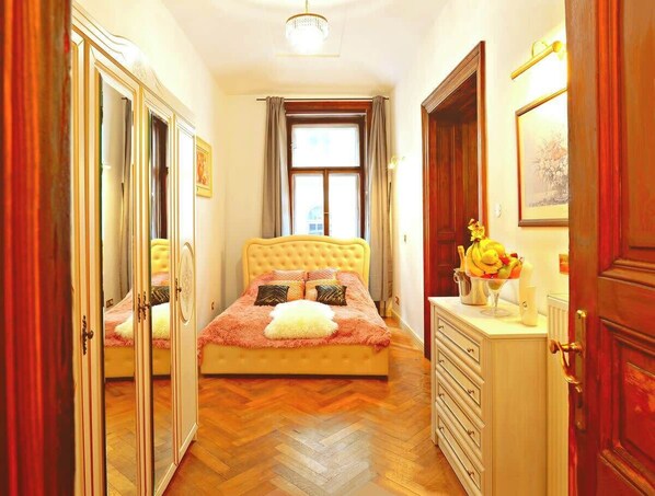 Ein Schlafzimmer mit Bett, Kommode, Spiegel und Fenster.