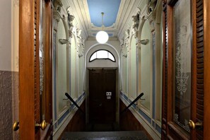A grand hallway with ornate columns, a large chandelier, and a door at the end. - Imperial Deluxe Suite (Prague)