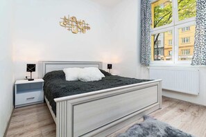 A bedroom with a bed, nightstands, a window with a view, and a wall decoration.
