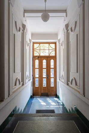 A hallway with a double wooden door with glass panels, leading to a room.
