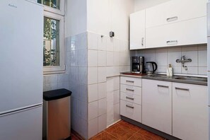 Cocina compacta con armarios blancos, encimera negra y ventana.