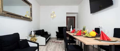 A modern dining area with a wooden table set for four, black upholstered chairs, and a black sofa.