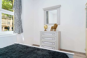Une chambre avec une commode blanche, un miroir, un globe terrestre et une statue de lion.